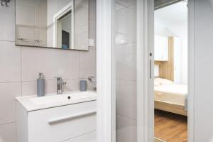 a white bathroom with a sink and a bedroom at Apartments Serzane in Zastražišće +62 photos
