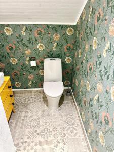 a bathroom with a toilet and floral wallpaper at Lyxig oas med modern elegans in Mora