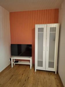 ein Wohnzimmer mit einem TV und einem weißen Schrank in der Unterkunft Top Apartment in Bielsko-Biała
