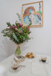a vase with flowers and cookies and two cups of coffee at Apartamento La Inmaculada in Ayamonte