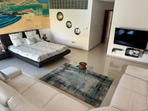 a living room with a couch and a bed and a tv at Family villa: pool and panoramic view in Praia
