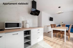 a kitchen with a table and a microwave at Apartamenty i Pokoje Gościnne Willa Dawid in Jastarnia