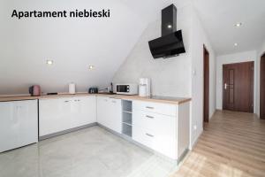 a kitchen with white cabinets and a tv on the wall at Apartamenty i Pokoje Gościnne Willa Dawid in Jastarnia