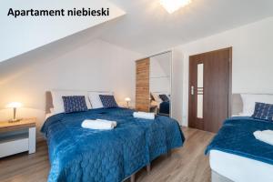 a bedroom with two beds with blue comforter at Apartamenty i Pokoje Gościnne Willa Dawid in Jastarnia