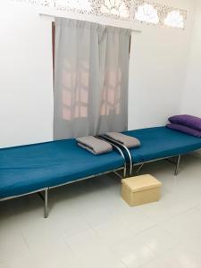 um quarto de hospital com uma cama azul e uma janela em House By the Palms em Kampong Sungai Rambai