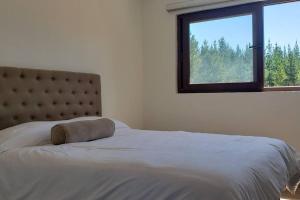 a bedroom with a bed with a large window at Casa en condominio de parcelas in Yumbel