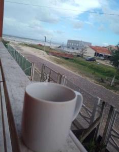 een koffiekopje op een vensterbank met uitzicht op het strand bij Apartamento Dúplex in Cidreira +2 foto's