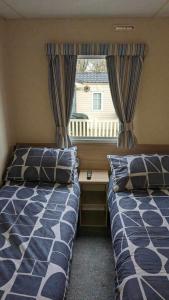 51 Oaklands caravan park dean thorness bay cowes في Porchfield: سريرين في غرفة صغيرة مع نافذة