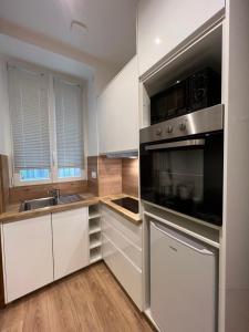 uma cozinha com armários brancos e electrodomésticos de aço inoxidável em Charme Cosy au Cœur de Paris em Paris