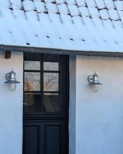 una casa con una puerta negra y dos luces en Le Roitelet - Suite d'hôtes privative en Montcavrel