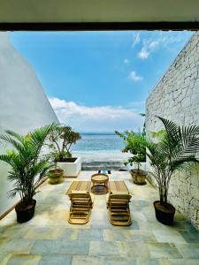 un patio con sedie, tavolo e vista sull'oceano di La Plage Onirique Beachfront Nusa Penida a Nusa Penida