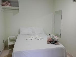 uma cama branca com lençóis brancos e toalhas em Pousada Chácara VIVALLI em Holambra