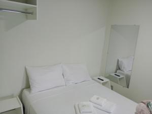 Cama blanca en una habitación pequeña con espejo en Pousada Chácara VIVALLI, en Holambra