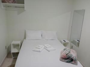 un letto bianco in una stanza bianca con due asciugamani di Pousada Chácara VIVALLI a Holambra