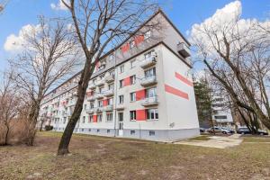 a large white building with red windows in a park at Air conditioned - 2 Room Apartment Ružinov in Bratislava