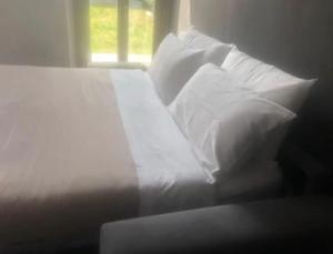 Cama blanca con almohadas blancas y ventana en [Medioevo con giardino] Lake Varese wifi Netflix, en Gavirate