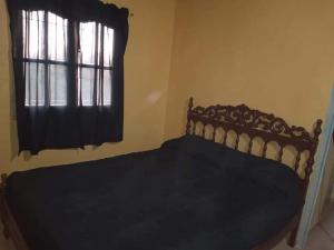 Schlafzimmer mit einem Bett und einem Fenster mit schwarzer Bettwäsche in der Unterkunft CABAÑA NUESTRO HOGAR in San Rafael