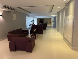 un largo pasillo con sofás y sillas en un edificio en Flat Palladium super aconchegante en São Vicente