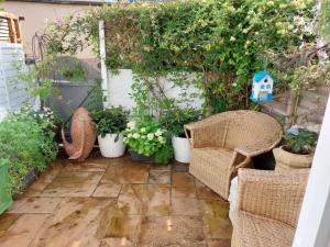 a patio with wicker chairs and potted plants at No2 Clarence grade II Regency townhouse short walk to racecourse and town centre in Cheltenham