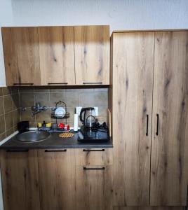 una cocina con armarios de madera y fregadero en Milano Apartman ****, en Brzeće