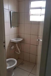 Un baño con inodoro, lavabo y espejo. en Apartamento em Muriqui - 203, en Mangaratiba