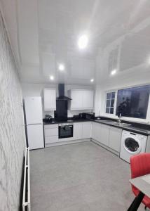 a kitchen with white cabinets and a washer and dryer at Rise at the International Wall Belfast in Belfast