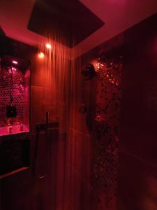 a dark bathroom with a shower with red lights at Love And Sex Room in Ferney-Voltaire