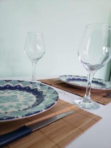 two wine glasses and plates on a wooden table at Apartamentos Pura Vida em Atlântida Sul in Xangri-lá