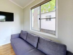 a couch in a living room with a large window at Poplar Tourist Park in Elderslie