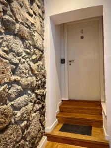 a hallway with a stone wall and a white door at A Muralha in Porto