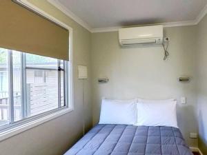 a bed in a room with a window at Camden Holiday Park in Camden