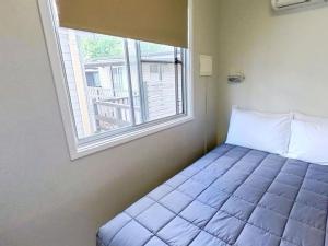 a bed in a room with a window at Poplar Tourist Park in Elderslie