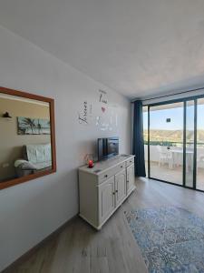 ein Wohnzimmer mit einem TV und einem Spiegel in der Unterkunft Paraíso Para Todos in Mogán