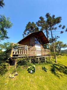 a large wooden cabin with a porch on a field at Pousada Recanto das Araucárias in Urubici