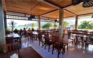 a restaurant with tables and chairs and a view of the ocean at Bungalow And Restaurant Anda in Kuta Lombok