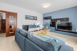 uma sala de estar com um sofá azul e uma cozinha em Casa del Mar - Piscina y Jacuzzi Privado em Costa Teguise