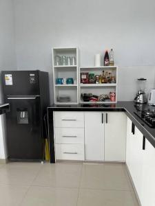 a kitchen with a black refrigerator and white cabinets at Casa Blanca cerca al Mar in Máncora