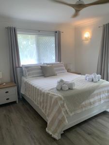 a bedroom with a large white bed with towels on it at Seabreeze at Silver Sands Hervey Bay in Hervey Bay