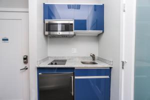 a kitchen with blue cabinets and a microwave and a sink at Cozy Studio on Newbury Street, #1 in Boston