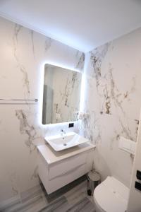 a white bathroom with a sink and a mirror at Dallga Suites in Tushemisht