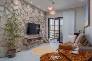 a living room with a stone wall with a tv at TOCA GAMBOA in Pôrto de Pedras