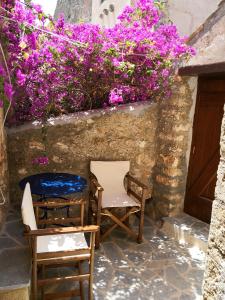 twee stoelen naast een muur met paarse bloemen bij Kissamitakis Guesthouse in Monemvasia