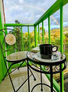un balcón verde con una taza de café sobre una mesa en Cuatro Gatos Casa Hotel, en Salento