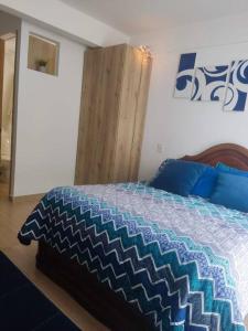 a bedroom with a bed with a blue and white quilt at Aparta estudio en la candelaria WiFi rápido-a pasos del museo de oro in Bogotá