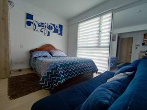 a bedroom with a bed and a couch and a window at Aparta estudio en la candelaria WiFi rápido-a pasos del museo de oro in Bogotá