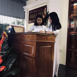 two women standing behind a wooden desk at Nhà nghỉ 1061 in Hai Phong