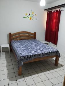 Cama pequeña en habitación con cortina roja en Casa em Tamandaré a 1km de Carneiros no Condomínio Cote d' Azur en Tamandaré