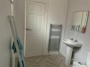 Baño blanco con lavabo y espejo en Family friendly flat, Perfect for a Dorset escape, en Bournemouth