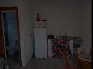 a small kitchen with a refrigerator and a sink at Wayak Flats PDR in Imbituba