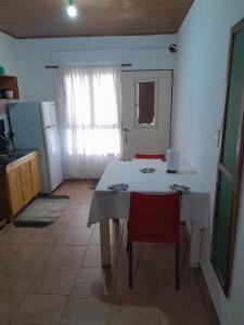 Una cocina con una mesa blanca y sillas rojas. en Departamento Itaembe Guazu, en Villa Dolores